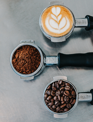 An aerial shot of a mug of coffee, a jar of ground coffee, and a jar of coffee beans