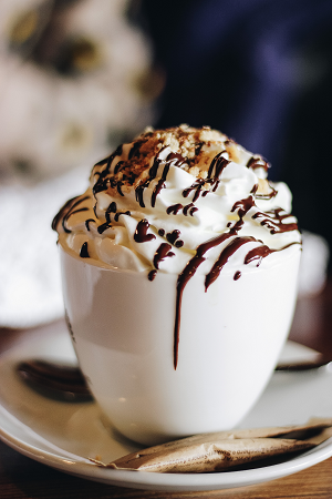 A custom-made drink, with whipped cream, chocolate sauce, and crushed hazelnuts